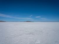 the salt has no clouds and a very small hill on it in the distance is a lake