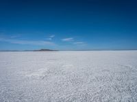 the salt has no clouds and a very small hill on it in the distance is a lake