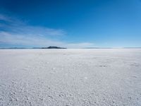 the salt has no clouds and a very small hill on it in the distance is a lake