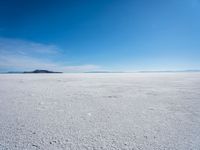 the salt has no clouds and a very small hill on it in the distance is a lake