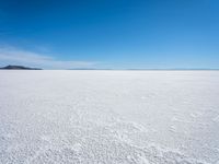 the salt has no clouds and a very small hill on it in the distance is a lake