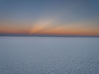 the sun is setting in the sky over the snowy field of ice snow is covered with snow