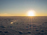 a bright, sun shines down over the snow - covered ground of a vast plain