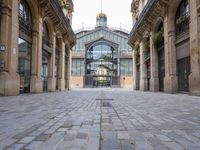 an outdoor market area with old stone flooring and an ornate clock tower on the building