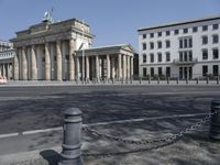 a woman riding a bicycle in the street next to some old buildings with pillars on each side and columns on either side