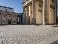 a large building on top of a brick building next to a couple of pillars holding columns