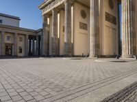 a large building on top of a brick building next to a couple of pillars holding columns