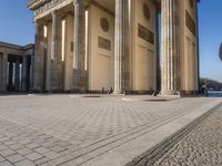 a large building on top of a brick building next to a couple of pillars holding columns