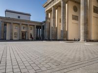 a large building on top of a brick building next to a couple of pillars holding columns