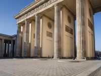 a large building on top of a brick building next to a couple of pillars holding columns