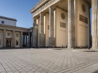 a large building on top of a brick building next to a couple of pillars holding columns