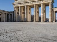 a large building on top of a brick building next to a couple of pillars holding columns