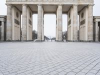 the people ride bicycles in front of the large building with many pillars and pillars behind it