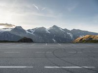 an empty parking lot with mountains in the background with a snow capped peak at the edge