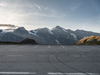 an empty parking lot with mountains in the background with a snow capped peak at the edge