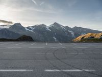 an empty parking lot with mountains in the background with a snow capped peak at the edge