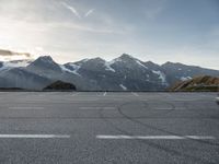 an empty parking lot with mountains in the background with a snow capped peak at the edge