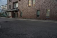 a brick building sitting next to an empty street with cars parked on the side of the road