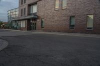 a brick building sitting next to an empty street with cars parked on the side of the road