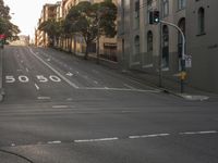 a wide empty road next to tall buildings on the sides of them with stoplights in one of them