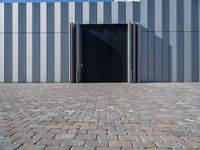 a door is opened in front of a wall with horizontal bricks on it and an area of sky