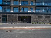 people walking outside of a large building with stone and glass on top of the roof