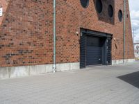 there is a black fire hydrant next to a brick building with doors that open