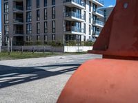 an orange fire hydrant on the side of a sidewalk and apartment buildings in the background