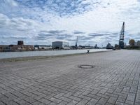 a brick walkway next to some water on a cloudy day looking out into the city