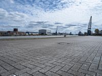 a brick walkway next to some water on a cloudy day looking out into the city