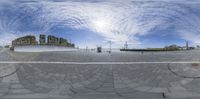 a fisheye lens shot of a wide paved square in a city area surrounded by buildings and a building