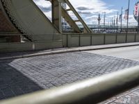 an old road on the side of the street in front of a bridge that stretches into a harbor