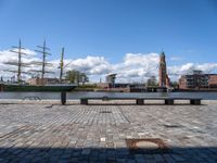 a large ship is in the harbor with buildings behind it and a bench at the front