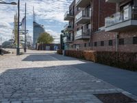 the paved street with buildings in the distance is lined with trees and bushes and two tall brick walles