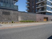 a view of a city street in front of an apartment building with a brick wall