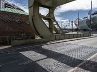 a bridge that crosses over the side of the road to access to a large boat in the distance