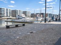 a boat docked at the port next to a bench in a harbor with a cloudy sky