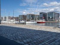 some white yachts docked in a marina with boats in the background and buildings on one side