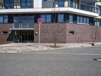 a stop sign near a building with windows on top of it that has a brick wall