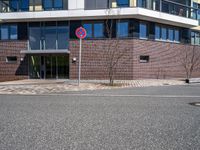 a stop sign near a building with windows on top of it that has a brick wall