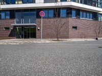 a stop sign near a building with windows on top of it that has a brick wall