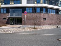 a stop sign near a building with windows on top of it that has a brick wall