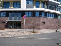 a stop sign near a building with windows on top of it that has a brick wall