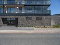 an urban building with some brick walled in area outside a fence and windows and balcony