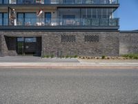 an urban building with some brick walled in area outside a fence and windows and balcony