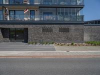 an urban building with some brick walled in area outside a fence and windows and balcony