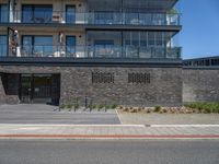 an urban building with some brick walled in area outside a fence and windows and balcony