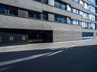 a empty street lined with tall black buildings on both sides of it and a sign that reads per 6