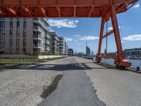 a street underneath the bridge next to a body of water in front of some large buildings