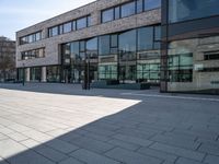 a empty courtyard in front of buildings on a sunny day with some cars on the ground